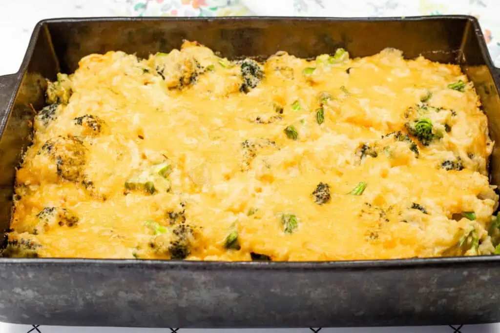 Freshly baked Broccoli Rice Casserole with Fresh Broccoli in a black baking dish, with a golden, bubbly layer of melted cheddar cheese on top.