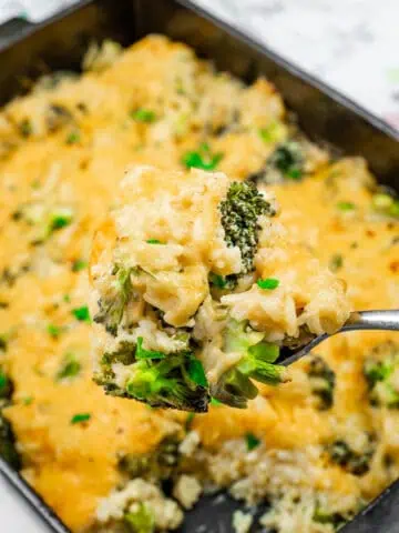 A spoonful of Broccoli Rice Casserole with Fresh Broccoli, with melted cheese, tender broccoli, and rice, garnished with fresh herbs.