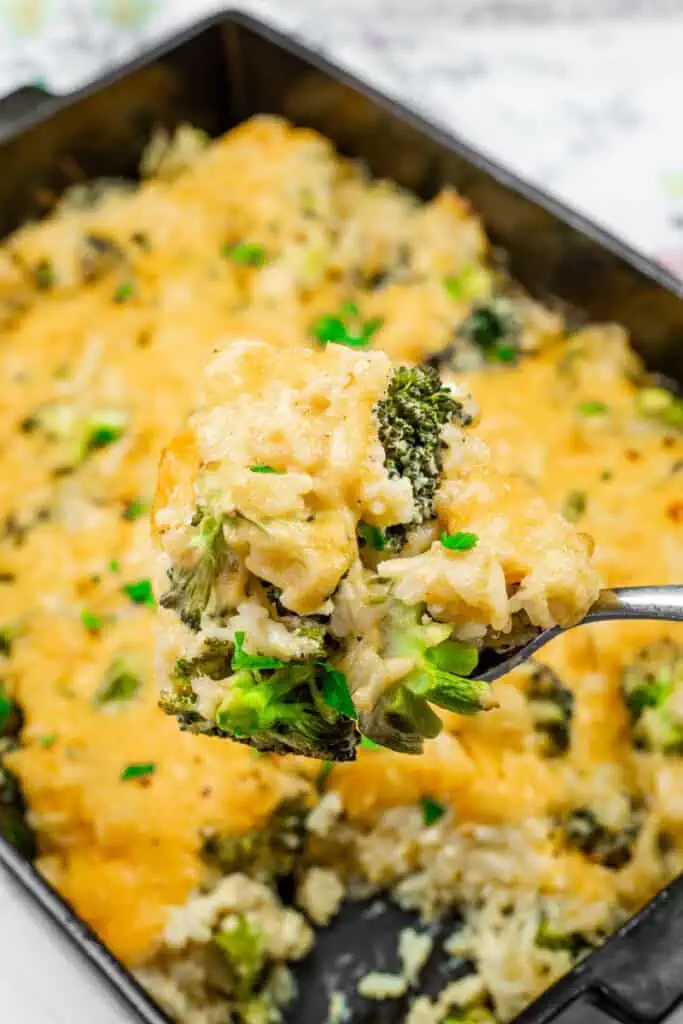 A spoonful of Broccoli Rice Casserole with Fresh Broccoli, with melted cheese, tender broccoli, and rice, garnished with fresh herbs.