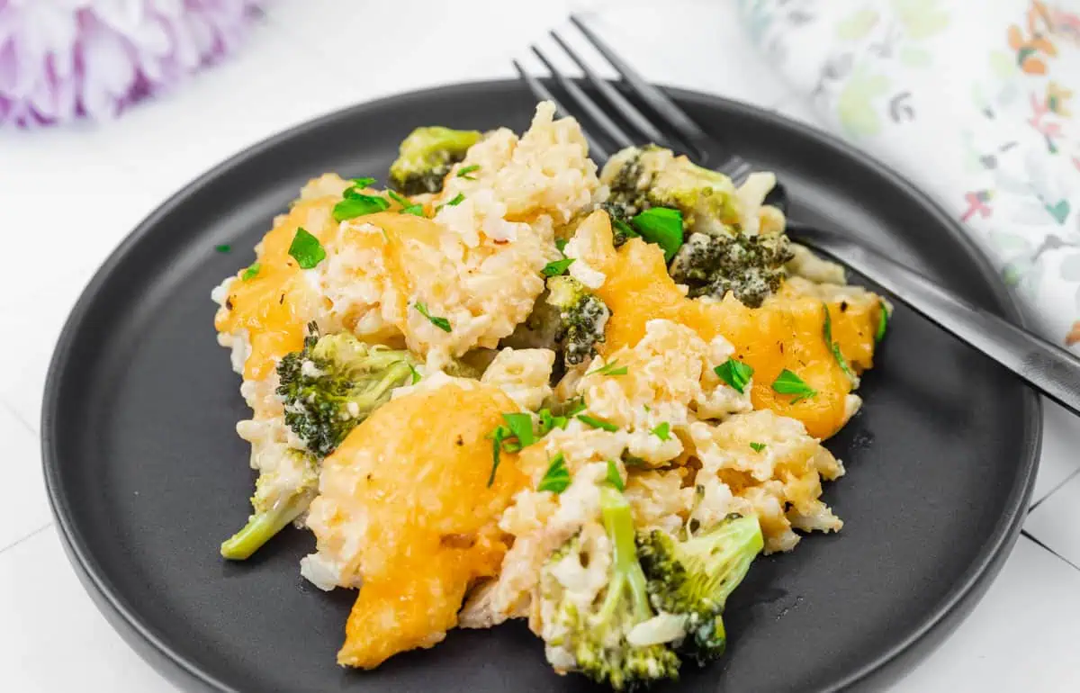 A serving of Broccoli Rice Casserole with Fresh Broccoli on a black plate.