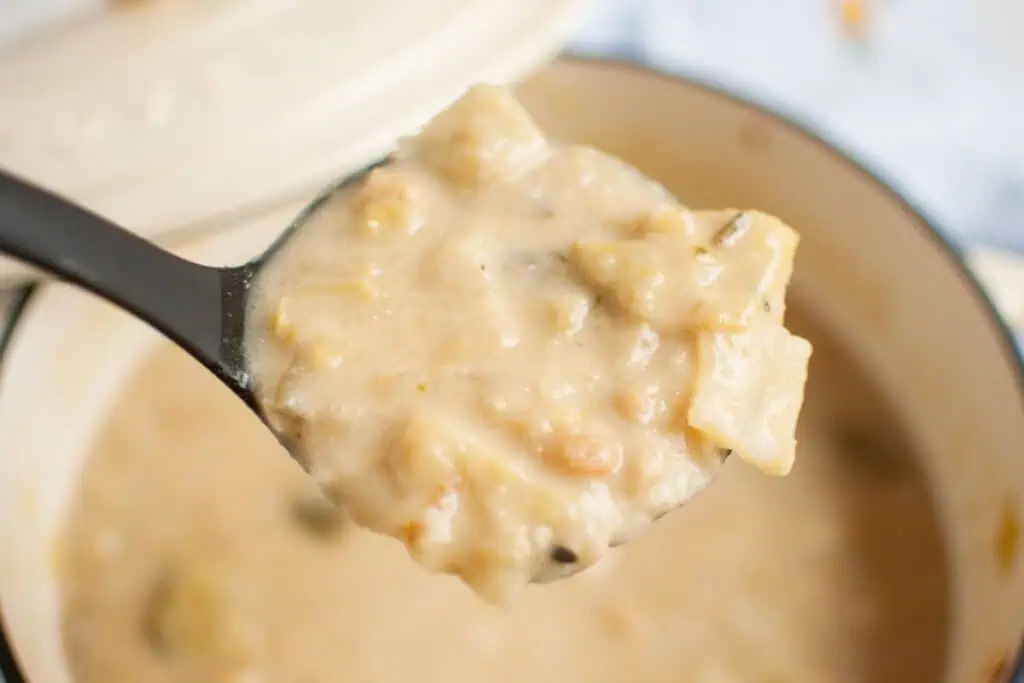 Ladle of creamy Cabbage and Bean Soup, held over a pot.