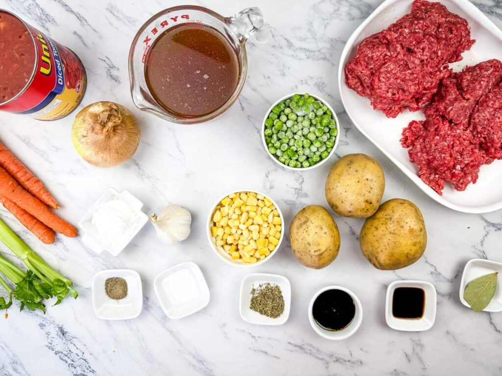 Ingredients for vintage hamburger stew are arranged on a marble surface.