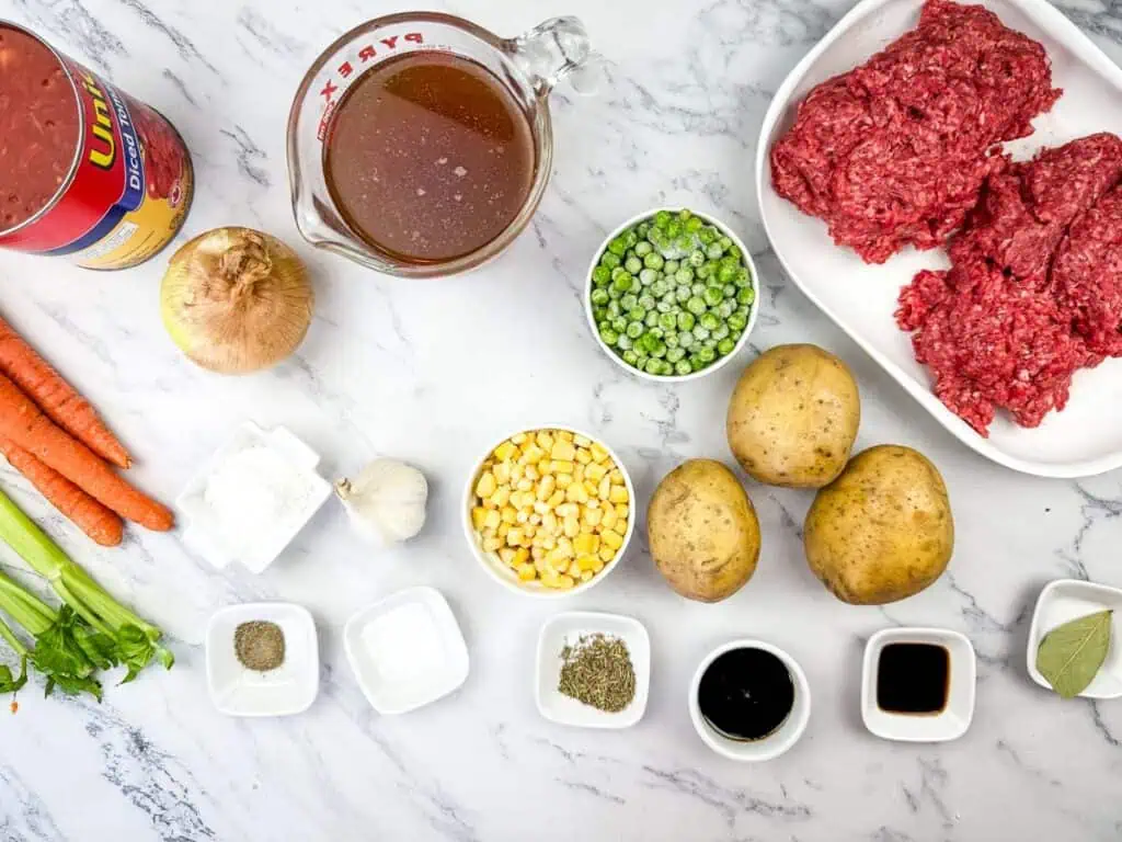 Ingredients for vintage hamburger stew are arranged on a marble surface.