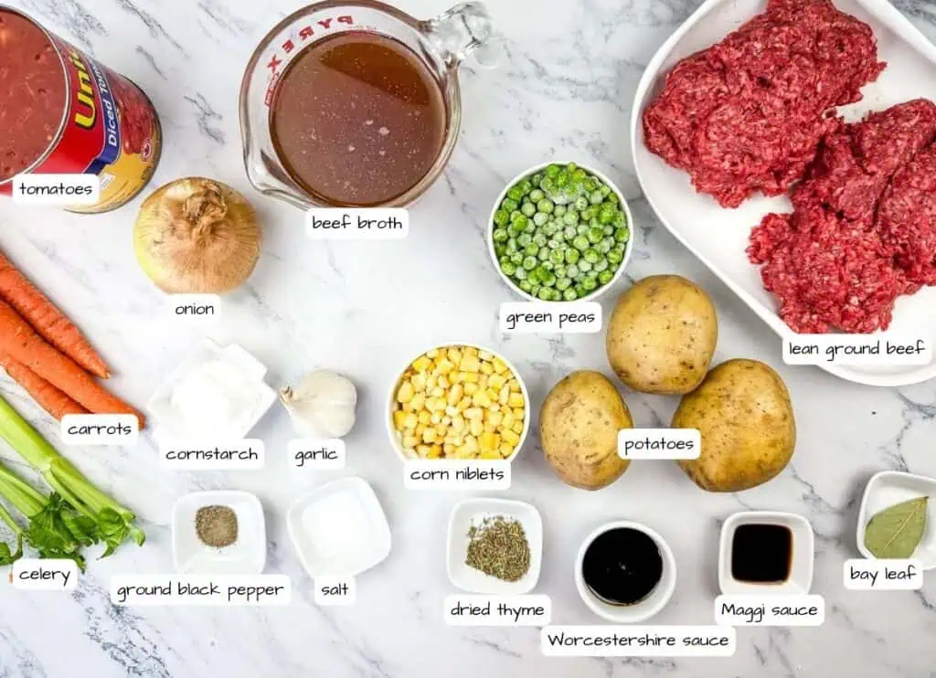 Ingredients for vintage hamburger stew are arranged on a marble surface with labels.