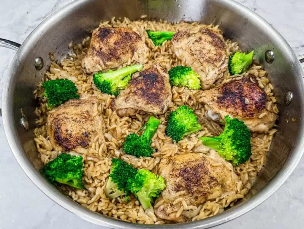 Skillet-cooked lemon chicken thighs with orzo pasta and vibrant broccoli florets, creating a flavorful and wholesome one-pan meal.
