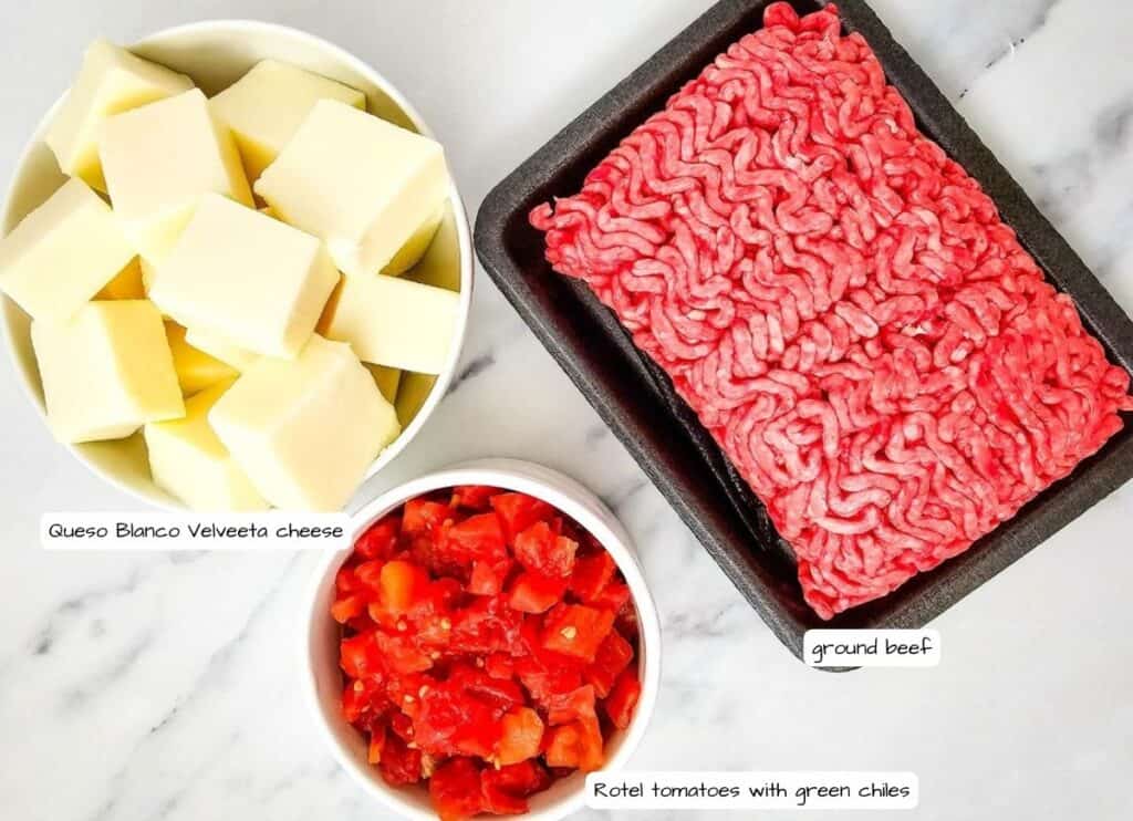 Bowls of Queso Blanco Velveeta cheese, Rotel tomatoes with green chiles, and a tray of ground beef on a marble surface.