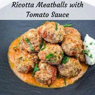 A serving of Ricotta Meatballs with Tomato Sauce on a black plate.