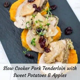 A serving of Slow Cooker Pork Tenderloin with Sweet Potatoes & Apples on a black platter.