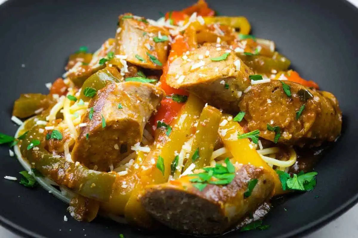 Slow cooker sausage and peppers garnished with grated cheese and chopped parsley.