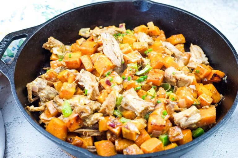 A cast-iron skillet with pulled pork and sweet potato hash.