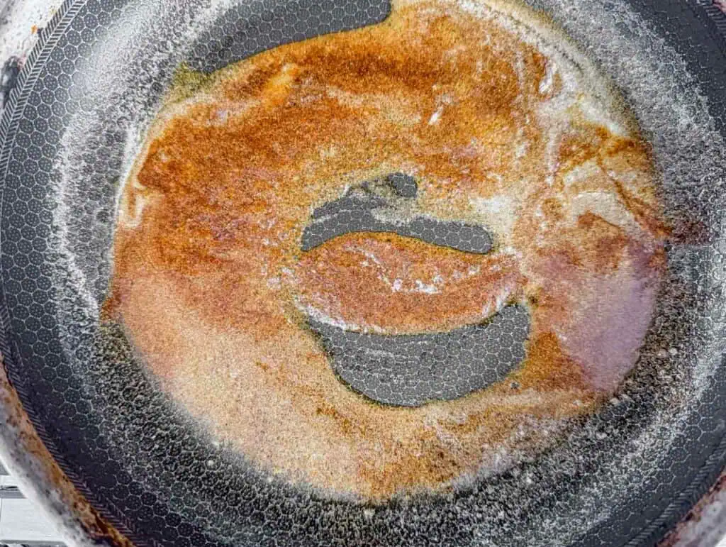 Close-up of a non-stick frying pan with a partially cooked, golden-brown crepe.