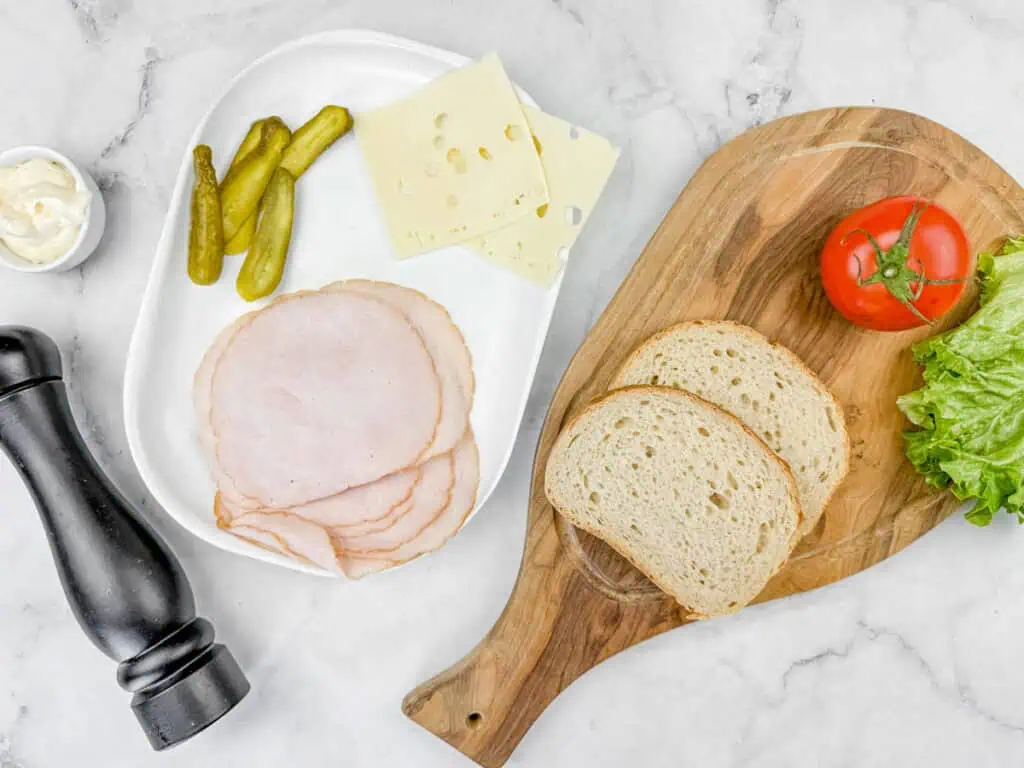 Ingredients of What She's Having Sandwich laying on top of white marble countertop.