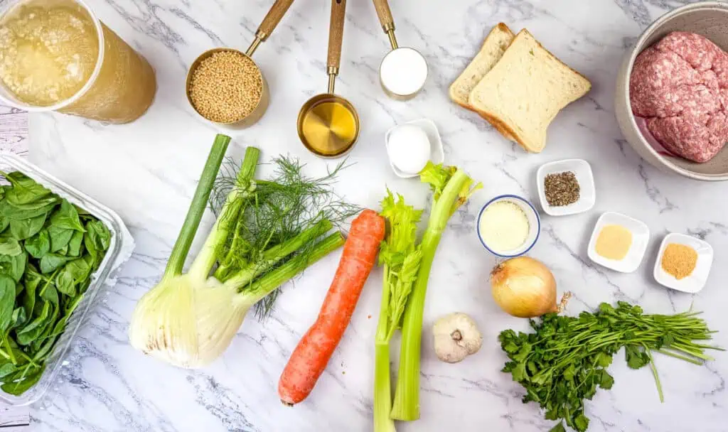 Ingredients for Italian Wedding Soup on a marble surface.