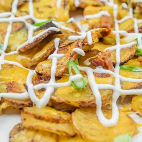Sliced, roasted potatoes topped with melted cheese, bacon bits, green onions, and drizzled with mayonnaise.