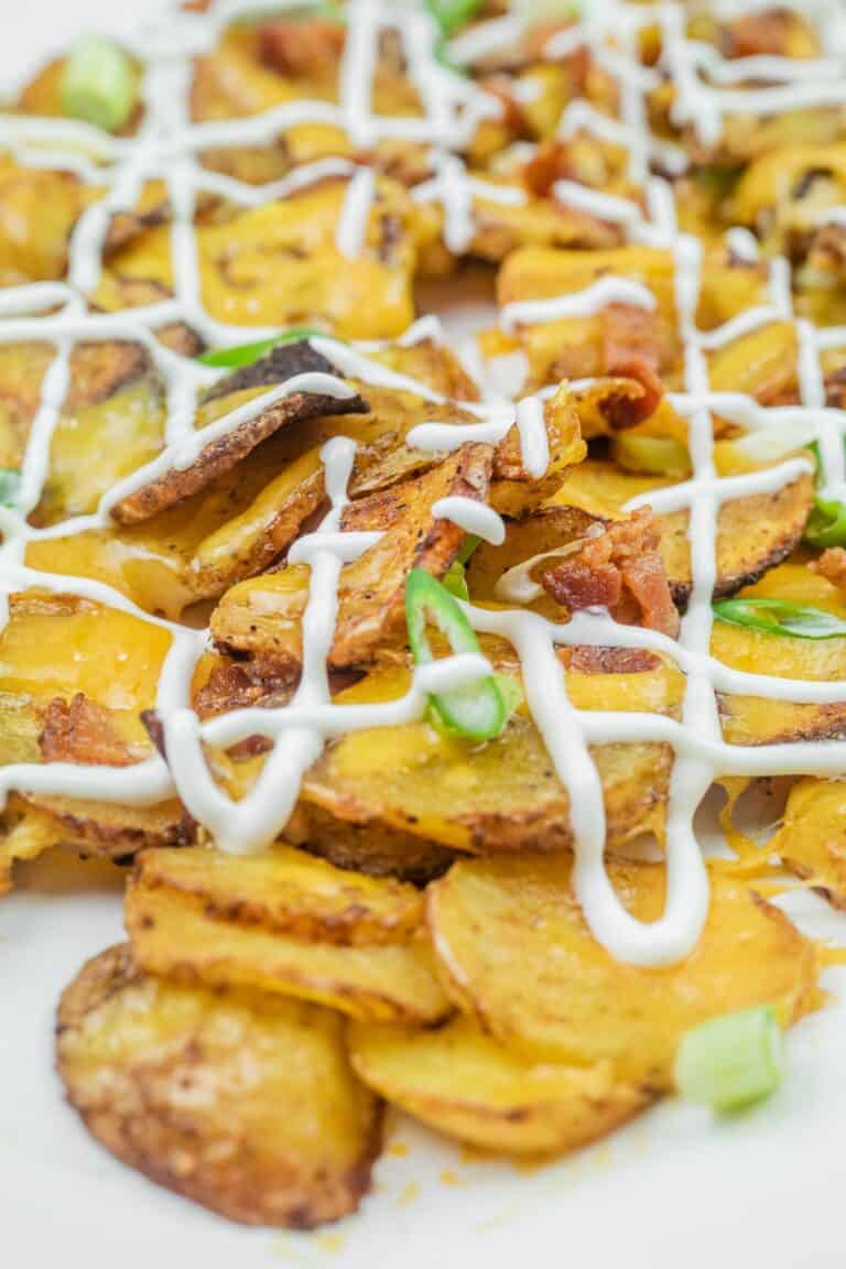 Sliced, roasted potatoes topped with melted cheese, bacon bits, green onions, and drizzled with mayonnaise.