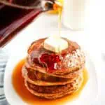 Syrup is poured onto a stack of Buttermilk Oatmeal Pancakes topped with a pat of butter.