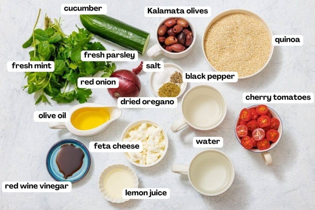 Ingredients for a Mediterranean salad: cucumber, Kalamata olives, quinoa, mint, parsley, red onion, oregano, tomatoes, feta, lemon juice, vinegar, olive oil, salt, pepper, water.