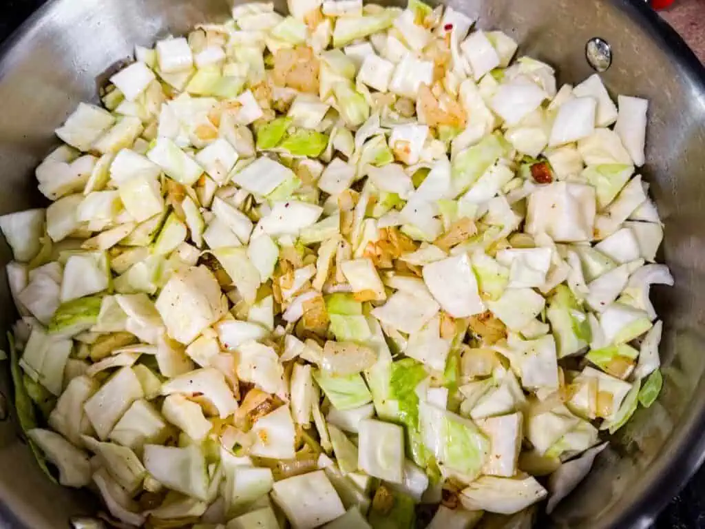 Chopped cabbage and onions cooking in a pan.