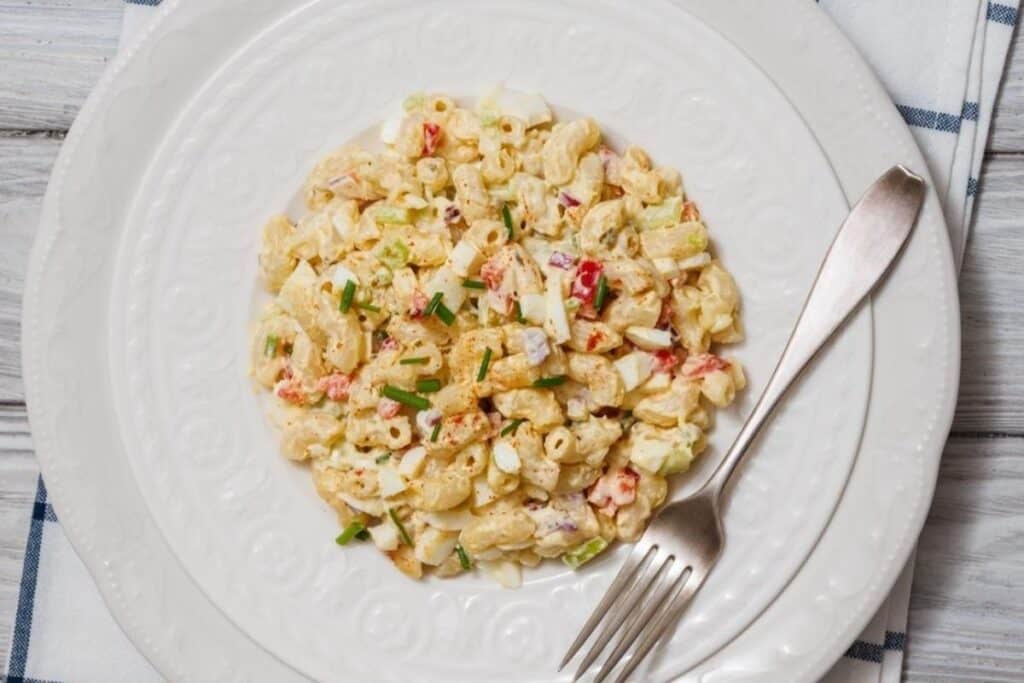 A plate of Deviled Egg Pasta Salad served on a white plate with a fork on the side.