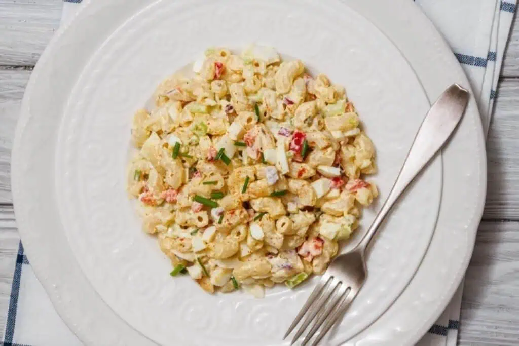 A plate of Deviled Egg Pasta Salad served on a white plate with a fork on the side.
