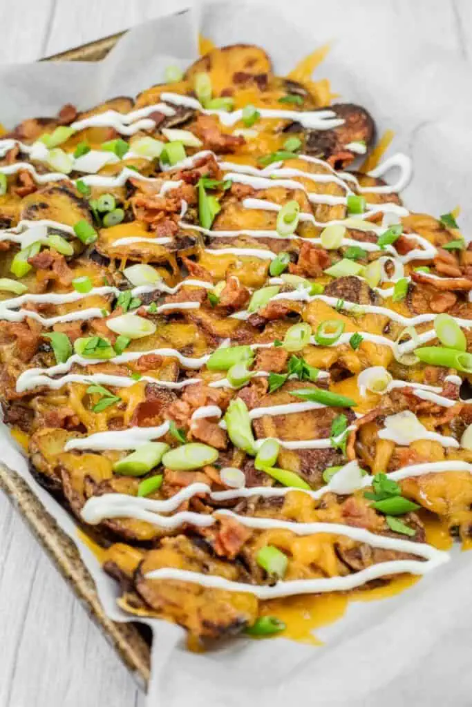 A tray of loaded Irish nachos topped with melted cheese, bacon, sliced green onions, and drizzled with sour cream.