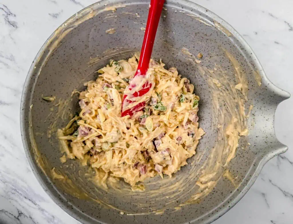 Bowl of mixed ingredients with a red spatula on a marble surface.