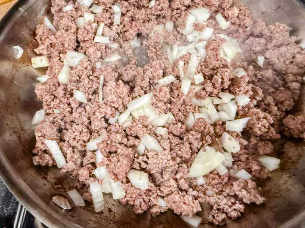 Ground meat and chopped onions cooking in a pan.