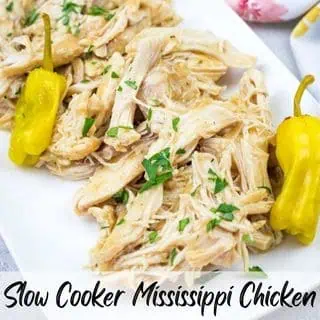 Slow Cooker Mississippi Chicken garnished with parsley and served with yellow peppers on a white plate. Text reads "Slow Cooker Mississippi Chicken.