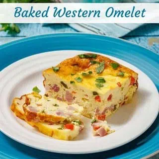 A slice of baked Western omelet with visible diced ham, red peppers, and green herbs sits on a white plate with a blue rim.