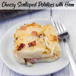 A serving of creamy Scalloped Potatoes with Ham and Cheese, topped with melted cheese and crispy browned bits, served on a white plate with a fork.