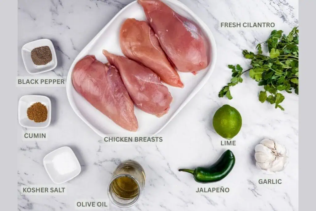 Raw chicken parts, Cilantro, lime, Jalapeno, garlic, oil, salt, cumin powder and black pepper on the surface with their names