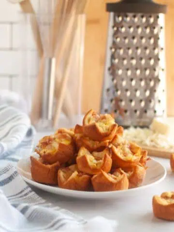 A white plate piled with small, golden-brown Ham and Cheese Puffs.