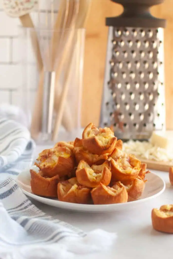 A white plate piled with small, golden-brown Ham and Cheese Puffs.