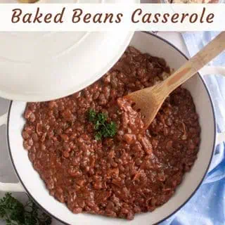 Overhead shot of a white casserole dish filled with baked beans, with a wooden spoon.