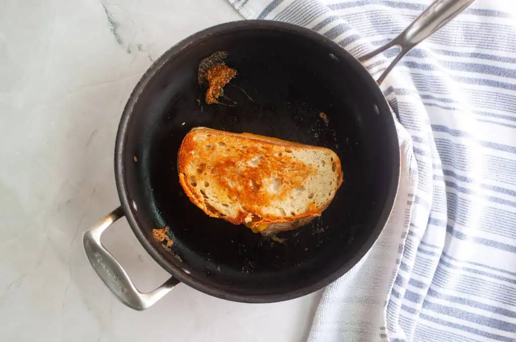 Overhead shot of a golden-brown grilled cheese sandwich in a black skillet.