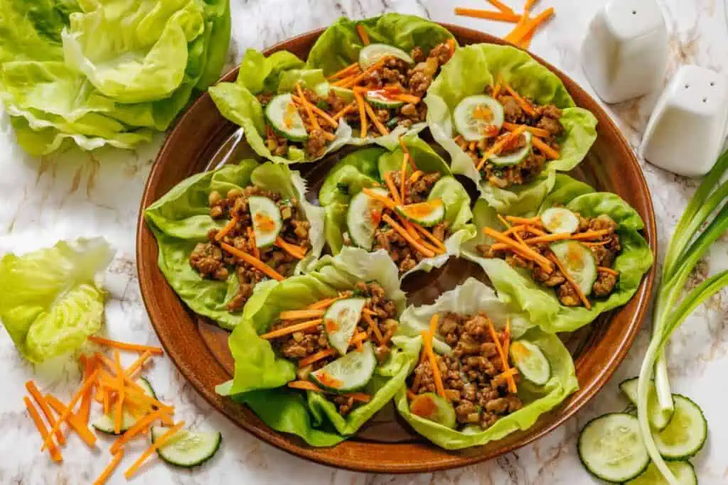 Lettuce wraps with meat and vegetables on a white table.