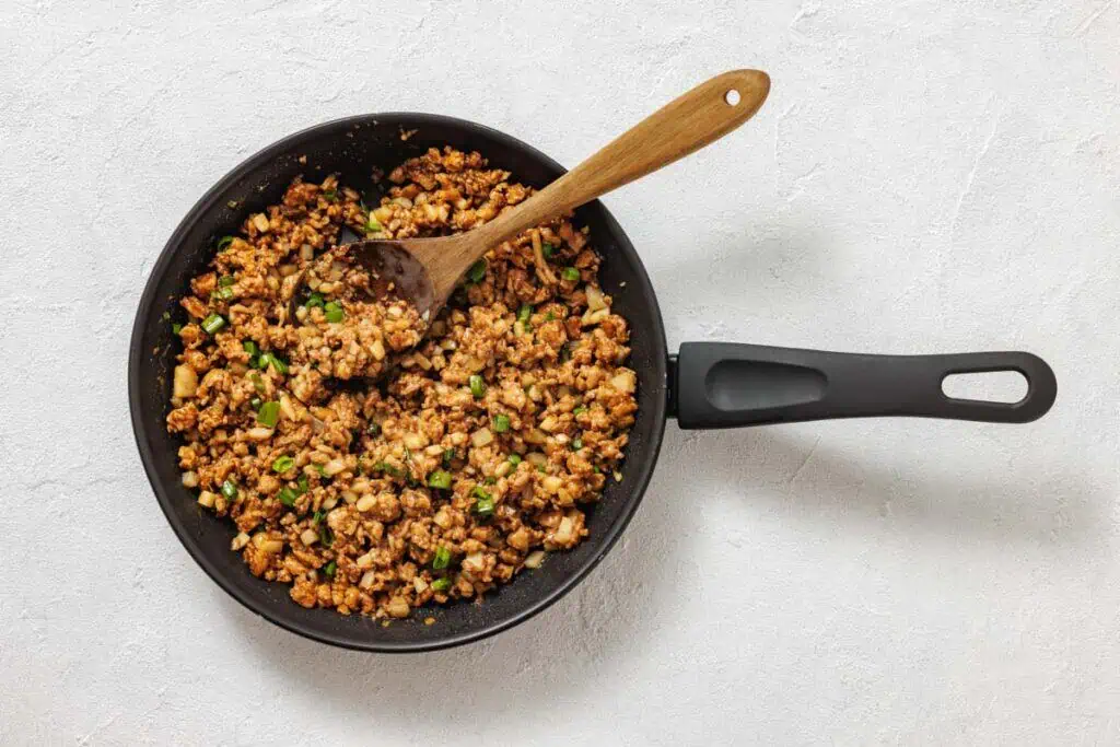 A pan filled with food and a wooden spoon.