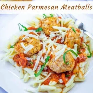 A plate of pasta topped with tomato sauce, chicken meatballs, shredded cheese, and fresh basil, labeled "Chicken Parmesan Meatballs.