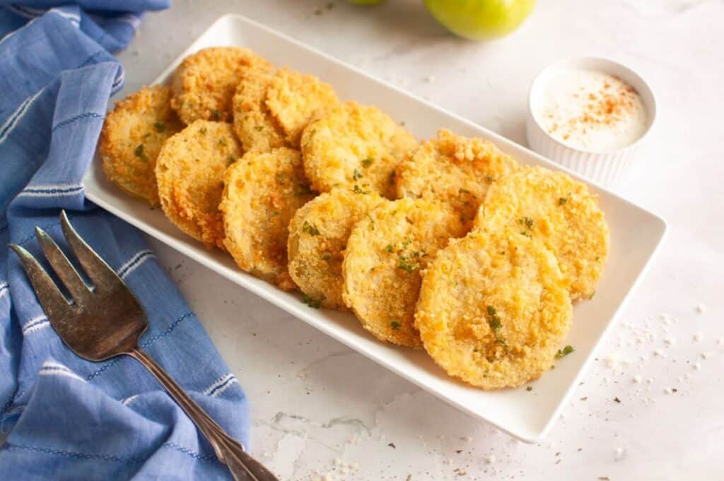 A plate of fried tomatoes with a fork.