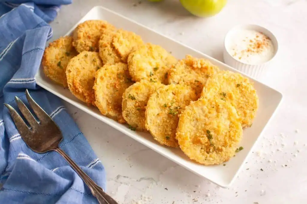 A plate of fried tomatoes with a fork.