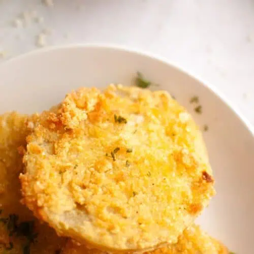 A white paper plate with several fried green tomatoes.