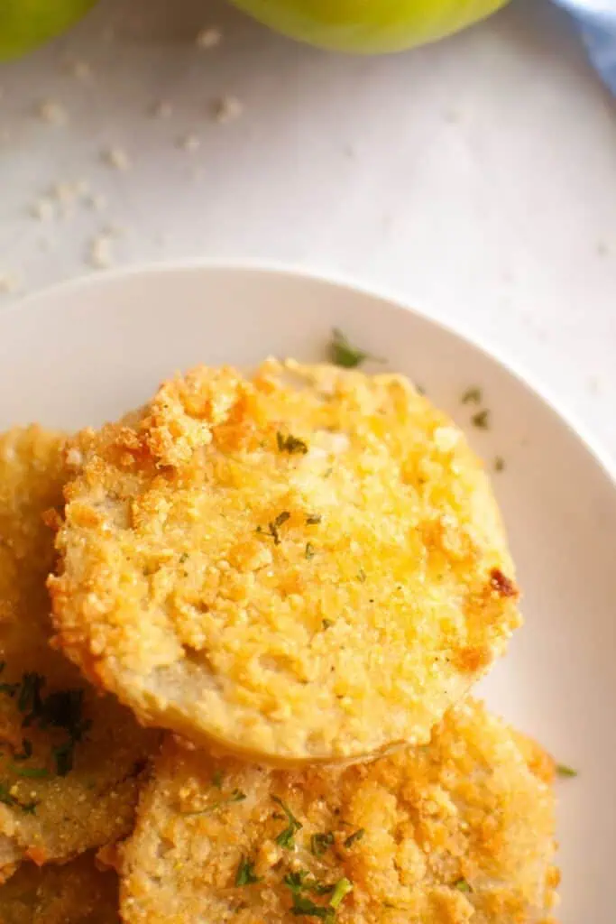 A white paper plate with several fried green tomatoes.