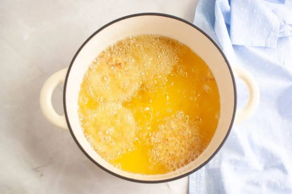 A pan filled with oil and eggs on a table.
