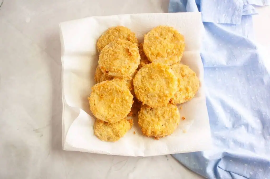 A white paper plate with several fried chicken nuggets.