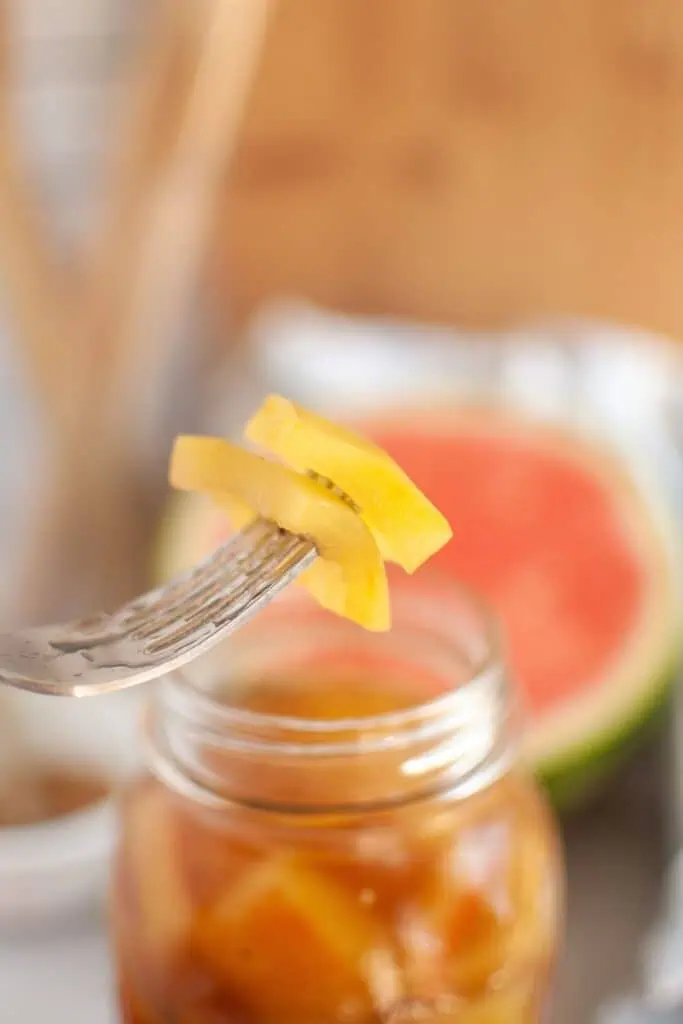 A fork is holding a piece of watermelon on a jar.