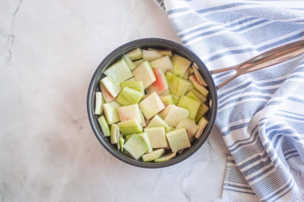 A pan filled with chopped apples on a white towel.