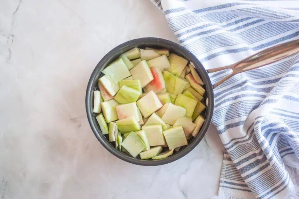 A pan filled with chopped apples on a white towel.