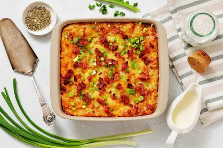 Grandma’s Twice-Baked Potato Casserole topped with chopped green onions and bacon, surrounded by fresh green onions.