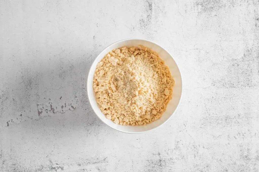A white bowl filled with mixture sits on a light gray textured surface.