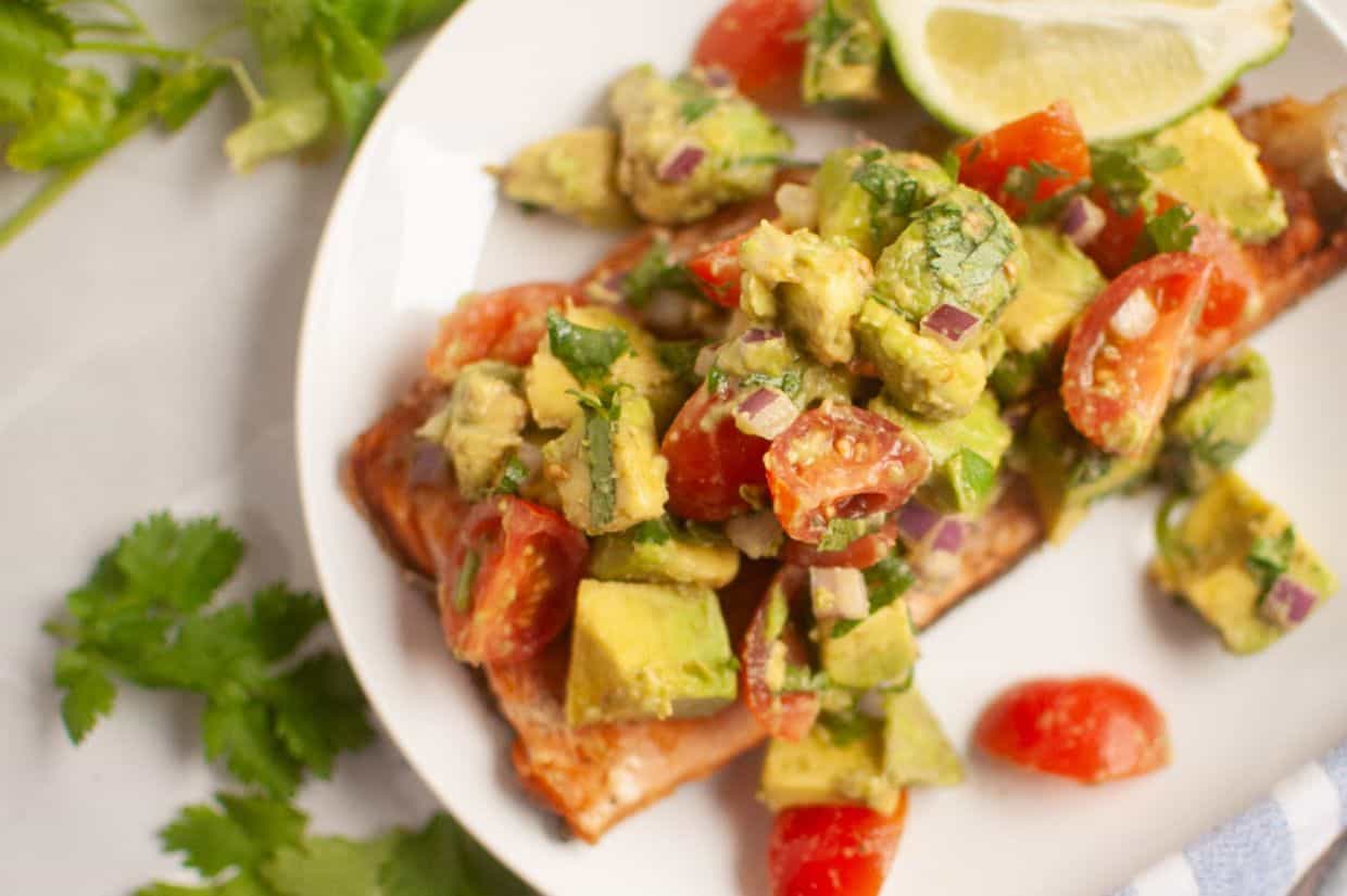 A plate of Seared Salmon with Avocado Salsa garnished with a lime wedge.